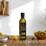 A sleek glass bottle of Mubarkah Extra Virgin Olive Oil displayed on a wooden kitchen counter next to fresh olives and a lemon. Premium quality cold-pressed oil